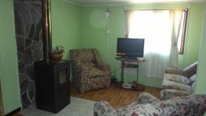 uma sala de estar com uma televisão, um sofá e uma cadeira em Cabañas Llaima em Melipeuco