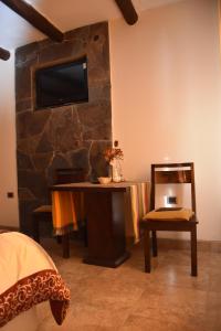 a bedroom with a desk and a tv on a stone wall at Refugio del Sol Hosteria in La Quiaca