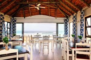 a restaurant with tables and chairs and a view of the ocean at Little Rock Guesthouse in Jongensfontein