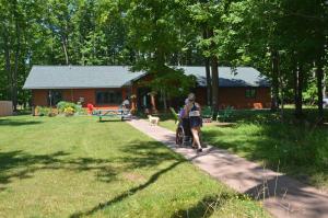a woman walking a bike down a path in front of a house at Namakagon Landing Condo in Cable