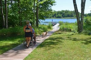 a woman walking a wheelchair down a path with a dog at Namakagon Landing Condo in Cable