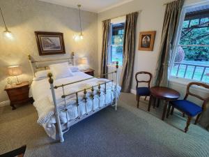 um quarto com uma cama e cadeiras e uma janela em The Ferry Bed & Breakfast em Queenstown