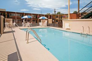 a swimming pool with chairs and umbrellas on a building at Americas Best Value Inn - Pendleton in Pendleton