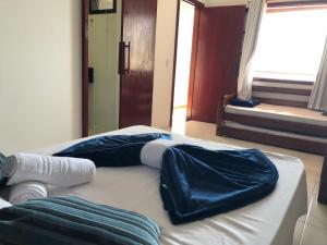 a bed with blue sheets on it in a room at Canto da Praia Suítes in Arraial do Cabo