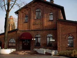 un edificio di mattoni rossi con un albero di fronte di REST HOTEL VARIA Działdowo a Działdowo