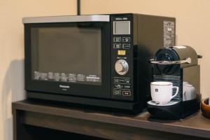 a microwave oven sitting on a shelf with a coffee cup at Miro Hachijo Genmachi Tei in Kyoto