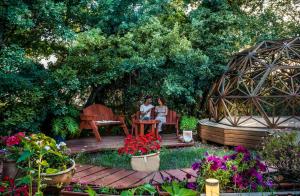 two women sitting on a bench in a garden at Spa in The Woods - B&B in Amirim in Amirim