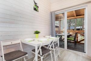 a white dining room with a table and chairs at Domki "Arkadia" in Pobierowo