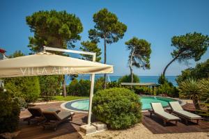 a patio with an umbrella and chairs and a pool at Villa Alma in Santa Margherita di Pula