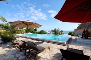 a swimming pool with chairs and a red umbrella at Mario Hotel and Cafe in Weetebula