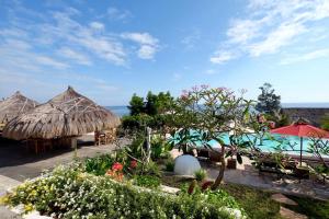 a resort with tables and umbrellas and the ocean at Mario Hotel and Cafe in Weetebula