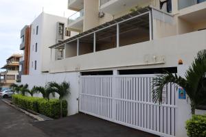 une maison blanche avec une porte blanche et des palmiers dans l'établissement Mahina Luxury 2 Bedroom Apartment with Pool, à Flic-en-Flac