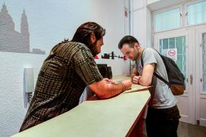 two men standing at a counter in an office at Pal's Mini Hostel in Budapest