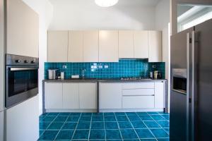 a kitchen with white cabinets and blue tile floors at Villa Alma in Santa Margherita di Pula