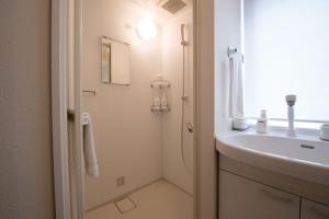 a white bathroom with a sink and a shower at Yukon in Kutchan