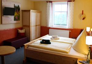 a bedroom with a bed and a table and a window at Landhaus Sonnentau in Johanngeorgenstadt
