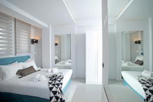 a white bedroom with two beds and a mirror at Imagine Studios in Paliouri