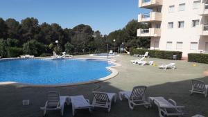 une piscine avec des chaises longues et un bâtiment dans l'établissement Apartamento Cap de Salou, à Salou