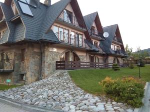 a large building with a stone path in front of it at Apartament Kasprowy in Kościelisko