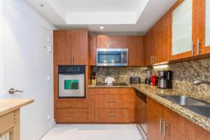 eine Küche mit Holzschränken, einer Spüle und einer Mikrowelle in der Unterkunft Two bed beach condo at Sian Miami in Hollywood