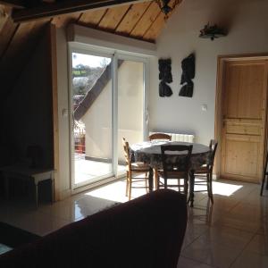 a dining room with a table and chairs and a window at Chez MARLENE in Quettehou