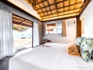 a bedroom with a large bed with a view of the beach at Balay Kogon in Carles