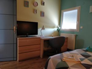 Schlafzimmer mit einem Schreibtisch, einem TV und einem Bett in der Unterkunft Chambre Chaleureuse chez l'habitant in Bourg-en-Bresse