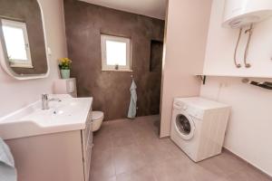een badkamer met een wastafel en een wasmachine bij 24 Punta in Sukošan