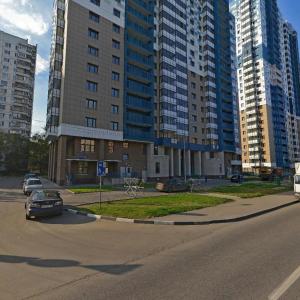 a city street with tall buildings and a car on the road at Apartment Hanaka Skryabina 8 in Moscow