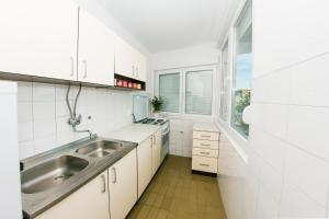 eine weiße Küche mit einem Waschbecken und einem Fenster in der Unterkunft Apartment Ella in Čapljina