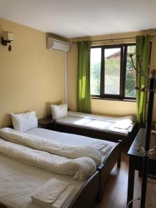 two beds in a room with green curtains at Complex Trakite in Elkhovo +53 photos
