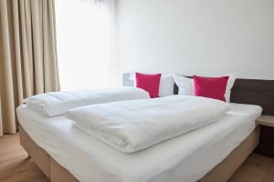 two beds with white sheets and red pillows at Hotel Calamus in Kehl am Rhein