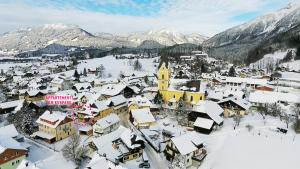 ein schneebedecktes Dorf mit Bergen im Hintergrund in der Unterkunft Appartements am Kurpark in Bad Mitterndorf