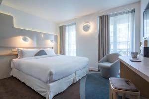 a hotel room with a large white bed and a chair at Hôtel Le Marcel Paris Gare de l'Est in Paris