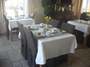 uma sala de jantar com duas mesas com toalha de mesa branca em Villa Cambo em Grandhan