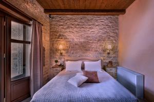 ネオ・イティロにあるPetra & Fos Boutique Hotel & Spaの石壁のベッドルーム1室(ベッド1台付)