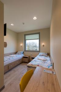 a room with two beds and a table and a window at Dom Żeglarza in Puck