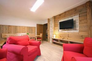 ein Wohnzimmer mit roten Stühlen und einem Flachbild-TV in der Unterkunft Almliesl ZELL-374 in Zell am See
