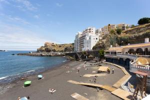a beach with people laying on the sand and the water at Studio Atlantic View in Icod de los Vinos