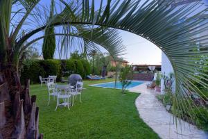 un jardín con mesa, sillas y piscina en Villa Tranquille, en Vence