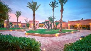 马拉喀什Palmeraie Dar Atlas - Luxury Houses的有棕榈树和建筑的庭院