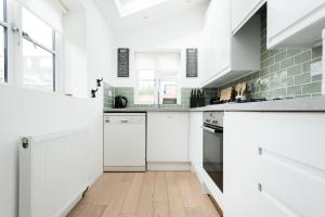 una cocina con armarios blancos y electrodomésticos blancos en The Old Tailor House - Charming 4BDR Home en Oxford