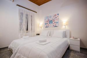 a white bedroom with a large white bed and a window at Villa Alexandra in Kissamos