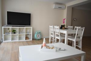 een woonkamer met een tv en een tafel en stoelen bij Alameda Centro Apartamento by TRG in Benidorm