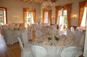 a room with white tables and chairs and chandeliers at SchlossHOTELGedern in Gedern