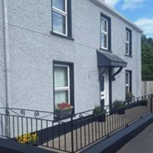 a white house with a black fence in front of it at Kesh self catering holiday home. in Kesh