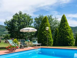 una piscina con 2 sillas y una sombrilla en Belvilla by OYO Agriturismo with garden, en Castiglion Fiorentino