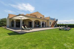 une maison avec des chaises et un parasol dans une cour dans l'établissement Mussol, à Sa Pobla