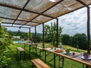 una pérgola de madera con mesas y sillas en un patio en Lovely farmhouse with swimming pool and air conditioning, en Sestino