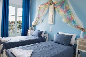 two beds in a room with blue walls at Aelia Studios in Koukounaries